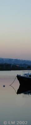 boat anchored in calm water at sunset